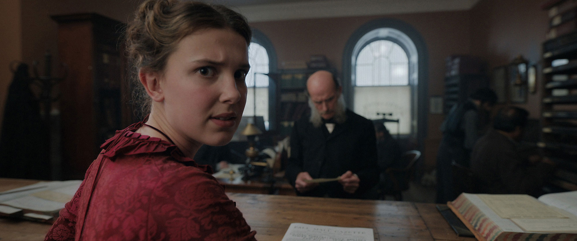Millie Bobby Brown como Enola Holmes, mirando hacia la cámara.