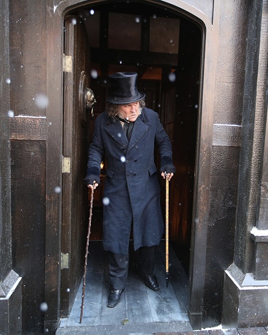 Johnny Depp como Scrooge saliendo de una puerta en la nieve.